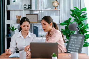 Modern ofis çalışma alanında iş birliği yapan iki genç ofis çalışanı, modern ofis çalışanı olarak profesyonelliklerini sergileyerek, dizüstü bilgisayarda tartışıyorlar ve birlikte çalışıyorlar. Coşkulu.