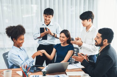 Çeşitli iş arkadaşları başarıyı şirket işyerindeki el sıkışma ve takım çalışmasıyla kutluyor. Çok kültürlü, mutlu profesyonellerden oluşan bir ekip ofiste tokalaşarak birlik oldular. Uyum