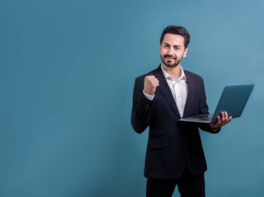 Yenilikçi teknoloji kavramına sahip başarılı bir iş adamı, ayakta duran, dizüstü bilgisayarı tutan ve telif alanı arka planında reklam ya da tanıtım için heyecanla gülümseyen. Coşkulu