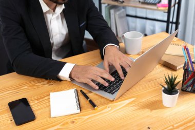 Modern ofis masasındaki modern profesyonel iş adamı çalışmak ve notlar yazmak için dizüstü bilgisayar kullanıyor. Ofisinde bilgisayar defteri üzerinde çalışan çalışkan bir ofis çalışanı. coşkulu