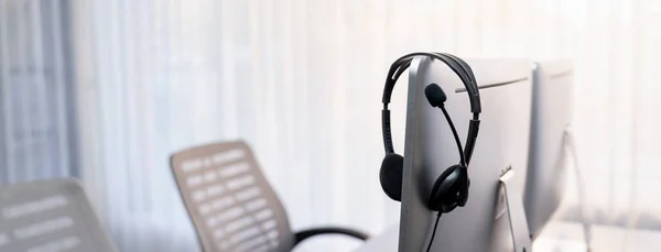 stock image Panorama view of empty call center operator workspace, focused on headset. Representing corporate customer service support and telesales communication technology. Prodigy