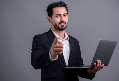 Yenilikçi teknoloji kavramına sahip başarılı bir iş adamı, kamerayı işaret eden ve dizüstü bilgisayarı tutan ve reklam ya da promosyon için arka planda heyecanla gülümseyen. Coşkulu