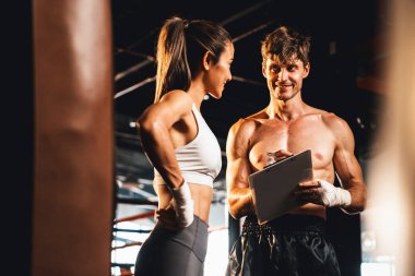 Asyalı bayan Muay Thai boksörü ve kişisel boks antrenörü spor salonundaki fiziksel ilerlemesini tartışıyor. Vücut kası gelişimine ve boks performansına bağlılığını yansıtıyor. Impetus