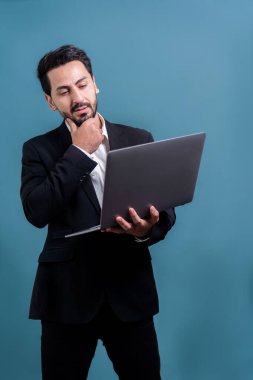 Yenilikçi teknoloji kavramına sahip başarılı bir iş adamı, ayakta duran, dizüstü bilgisayarı tutan ve telif alanı arka planında reklam ya da tanıtım için heyecanla gülümseyen. Coşkulu