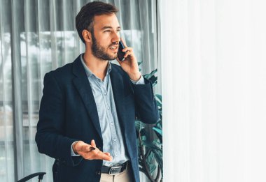 Çalışkan iş adamı, modern ofiste güvenilir bir şekilde müşteriye ikna edici satış çağrıları yapıyor. Ofis çalışanı telefonda konuşuyor ve iş arkadaşlarıyla iş görüşmesi yapıyor. Varlık