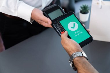 NFC QR kod cihazı ile el ele tutuşan akıllı telefon, hızlı dijital işlemler için temas kurulamayan ödeme kodlarını tarıyor. Modern yaşam tarzı ödeme teknolojisi için cep telefonundaki online bankacılık uygulaması. coşkulu