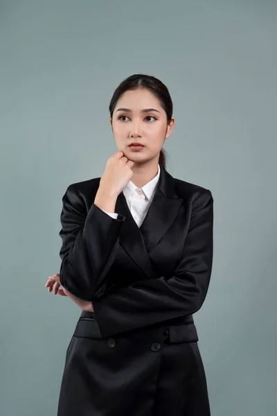 Stock image Confident young businesswoman stands on isolated background, posing in formal black suit. Office lady or manager with smart and professional appearance. Enthusiastic