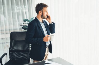 Çalışkan iş adamı, modern ofiste güvenilir bir şekilde müşteriye ikna edici satış çağrıları yapıyor. Ofis çalışanı telefonda konuşuyor ve iş arkadaşlarıyla iş görüşmesi yapıyor. Varlık