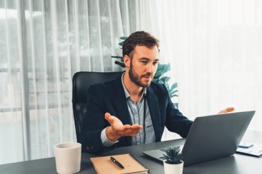 İşadamı ofis masasından sanal ofis toplantısı düzenliyor ve uzaktan çalışanlarla uzak iletişim kurmak için dizüstü bilgisayardaki Webinar uygulamasını kullanarak çevrimiçi video konferansını tartışıyor. Varlık