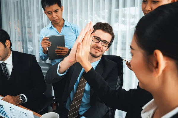 Group of happy businesspeople in high five gesture and successful efficient teamwork. Diverse race office worker celebrate after made progress on marketing planning in corporate office. Habiliment