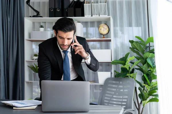 勤勉なビジネスマンは 携帯電話で現代の勤勉なオフィスワーカーのライフスタイルの概念として彼のオフィスでラップトップで作業しながら クライアントと電話で話を忙しい フェルベント — ストック写真