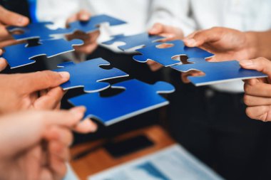 Çok ırklı iş adamları yapboz parçalarını tutuyor ve onları etkili çözüm çözümleri olarak birleştiriyor takım çalışması, ortak görüş ve çeşitli yetenekleri birleştiren ortak hedef. Çok titiz.