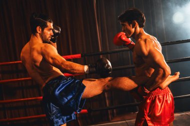 Asyalı ve Kafkasyalı Muay Thai boksörü sert boks maçında tekme sallarken savunma pozisyonundaki rakip acımasız dövüş hünerleriyle tekme bacağını tutuyor. Impetus