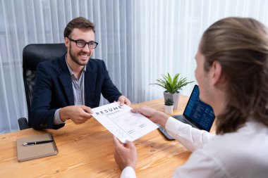 Aday özgeçmişini ya da CV 'yi şirket toplantı odasında mülakata veriyor. İş başvurusunda bulunan kişi, iş tecrübesini ve niteliğini İK müdürüne göstermemiş. Varlık