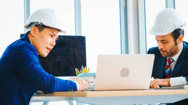 Mühendis ve mimar, mühendislik ve mimari proje planlaması hakkında ofis masasında toplanıyorlar. Jivy