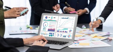 Analizci ekibi yaratıcı ve analitik beyin fırtınası fikri için bilgisayar ekranında BI veri paneli olan yapışkan bir not kullanıyor. Pazarlama stratejisi için finansal veri görselleştirme teknolojisini analiz et. Dahi.