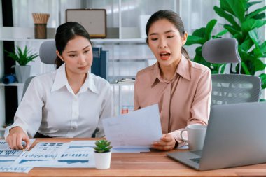 Modern ofis çalışma alanında iş birliği yapan iki genç ofis çalışanı, modern ofis çalışanı olarak profesyonelliklerini sergileyerek, dizüstü bilgisayarda tartışıyorlar ve birlikte çalışıyorlar. Coşkulu.