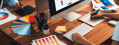 Grafik tasarımcısı, modern dijital stüdyo işyerinde profesyonel grafik ekibiyle benzersiz bir tasarım yaparken bilgisayar dizüstü bilgisayar ve grafik çizim kalemi üzerinde çalışır. Panorama çekimi. İnceleyin