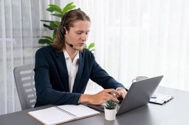 Erkek müşteri hizmetleri operatörü ya da telesales temsilcisi ofiste oturuyor, kulaklık takıyor ve müşteriyle satış desteği ya da kapanış konuşması yapıyor. Çağrı merkezi portresi. Varlık
