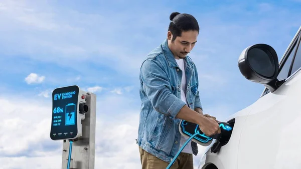 Азіатський Чоловік Вставляє Зарядний Пристрій Заряджає Електричний Автомобіль Енергією Від — стокове фото
