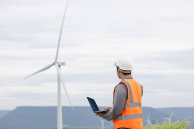 Kırsal kesimdeki bir tepenin tepesinde ya da dağda rüzgar çiftliğinde çalışan bir mühendis. Yenilenebilir ve sürdürülebilir enerjinin gelecekteki üretimi için yenilikçi bir ideal. Rüzgar türbininden enerji üretimi.