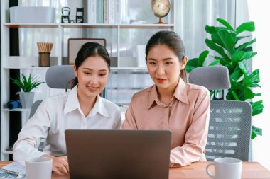 Modern ofis çalışma alanında iş birliği yapan iki genç ofis çalışanı, modern ofis çalışanı olarak profesyonelliklerini sergileyerek, dizüstü bilgisayarda tartışıyorlar ve birlikte çalışıyorlar. Coşkulu.