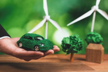 Ofiste yeşil eko araba modelini tutan bir iş adamı. Çevre dostu taşımacılık için kullanılan elektrikli bir araç. CO2 emisyonu sıfır olan bir şirket. Değiştir