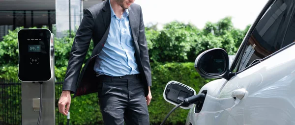Progressive Businessman Wearing Black Suit Electric Car Recharging Public Parking — Zdjęcie stockowe