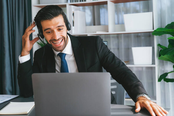 Male call center operator or telesales representative siting at his office desk wearing headset and in conversation with client providing customer service support or making persuasive sale. fervent
