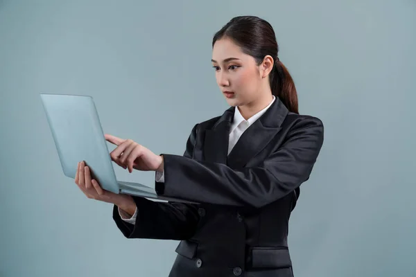 自信的年轻女商人站在孤立的背景上 穿着正式的黑色西服在笔记本电脑上工作 办公室女职员或经理 外表聪明 很有激情 — 图库照片