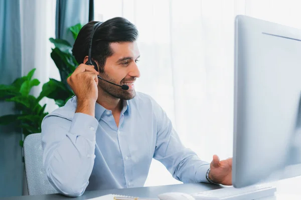 stock image Male call center operator or telesales representative siting at his office desk wearing headset and engaged in conversation with client providing customer service support or making a sale. fervent