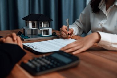 Ev kredisi sürecinin son aşamasını tamamlayan alıcı, kredi sözleşmesini masanın üzerinde bir kalemle imzalayarak mülkün mülkiyetini güvence altına alıyor. Coşkulu.