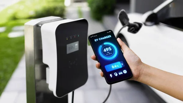 スマートフォンはスマートEvモバイルアプリケーションのバッテリーステータスを表示し Ev車はガレージ内の家庭用充電ステーションで電気を充電します 将来の革新的なEv車とエネルギー持続可能性 Peruse — ストック写真
