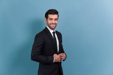 Siyah takım elbiseli şık bir işadamı, mutlu ve iyimser bir gülümseme ile izole bir arka planda güvenle poz veriyor iş adamlarının başarısı ve profesyonelliği gibi. Coşkulu