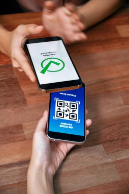 QR kodu parasız ödeme taraması için ekranda gösterilir. Kapalı eller, mobil uygulamadan elektronik işlem yoluyla para aktarmak için akıllı telefonu tutuyor. Hızlı ödeme için barkod teknolojisi. Coşkulu.