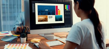 Grafik tasarımcısı, modern dijital stüdyo işyerinde profesyonel grafik ekibiyle benzersiz bir tasarım yaparken bilgisayar dizüstü bilgisayar ve grafik çizim kalemi üzerinde çalışır. Panorama çekimi. İnceleyin