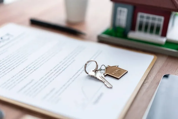 House key on top of house loan or mortgage contract document over table in office as symbolic of successful property ownership transfer. Home ownership and legal contract binding agreement. Jubilant