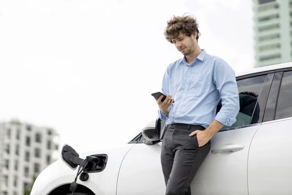 Progressive Businessman Talking Phone Leaning Electric Car Recharging Public Charging — Stock Fotó