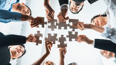 Çok ırklı iş adamları yapboz parçalarını tutuyor ve onları etkili çözüm çözümleri olarak birleştiriyor takım çalışması, ortak görüş ve çeşitli yetenekleri birleştiren ortak hedef. Görüş alanının altında. Habiliment