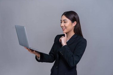 Özgüvenli genç Asyalı iş kadını dizüstü bilgisayarla izole edilmiş arka planda poz veriyor. Ofisteki kadın terfi satışları, teknoloji reklamları ya da insan kaynakları için el ele tutuşmalar yapıyor. Sevinçli.