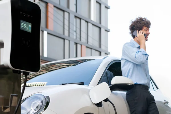 Progressive Businessman Talking Phone Leaning Electric Car Recharging Public Charging — Stok fotoğraf