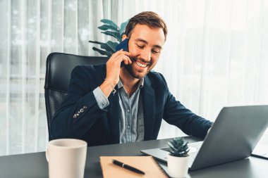 Çalışkan ve çalışkan iş adamı, cep telefonuyla müşterileriyle konuşurken, modern çoklu görev yapan ofis çalışanı yaşam tarzını sergiliyor. Varlık