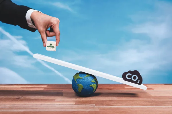 Businessman weigh solar panel icon on scale against a CO2 symbol, promoting zero CO2 emission. Sustainable approach to clean energy for green ecology and environment as corporate responsibility. Alter