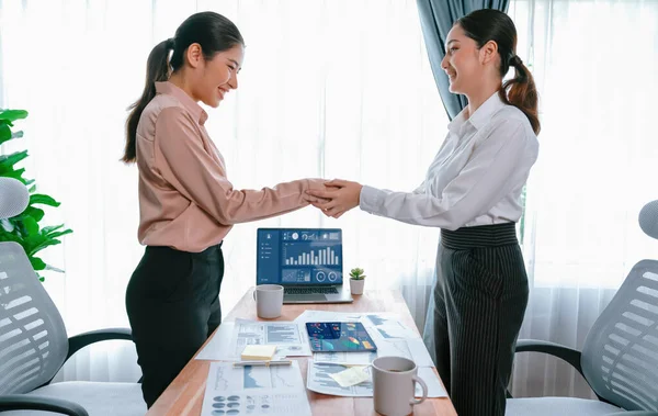 两名亚洲女商人在成功地分析了成堆的仪表盘数据文件之后 在现代办公室里握手 这是团队合作和诚信在工作场所概念中的重要性 很有激情 — 图库照片