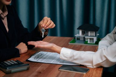 Emlakçı, ev kredisi anlaşmasının başarıyla tamamlanmasının ardından, yeni bir ev hayalinin hayata geçirilmesinin bir simgesi olarak alıcıya anahtarı teslim etti. Coşkulu.