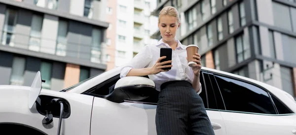 Focus Businessman Using Phone Leaning Electric Vehicle Holding Coffee Blurred — Foto de Stock
