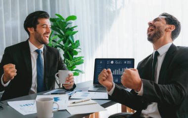 Heyecanlı iş ekibi masadaki Fintech BI gösterge panelinin başarılı analizini kutluyor. Kazanan takım, dizüstü bilgisayarda veri grafiği görüntüsü ile neşeyi ifade eder. Başarılı analist takım çalışması. Coşkulu