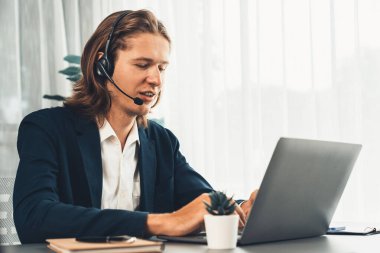 Erkek müşteri hizmetleri operatörü ya da telesales temsilcisi ofiste oturuyor, kulaklık takıyor ve müşteriyle satış desteği ya da kapanış konuşması yapıyor. Çağrı merkezi portresi. Varlık