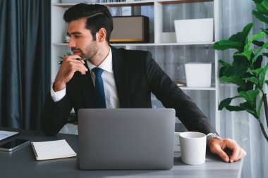 Modern ofis masasındaki modern profesyonel iş adamı çalışmak ve notlar yazmak için dizüstü bilgisayar kullanıyor. Ofisinde bilgisayar defteri üzerinde çalışan çalışkan bir ofis çalışanı. coşkulu