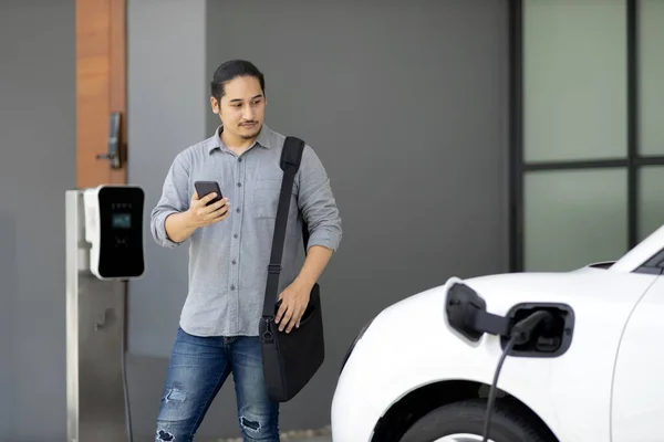 Progressive Asian Man Electric Car Home Charging Station Concept Use — Foto Stock
